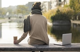 Nachdenkliche Frau mit Kopfhörer an einem Fluss